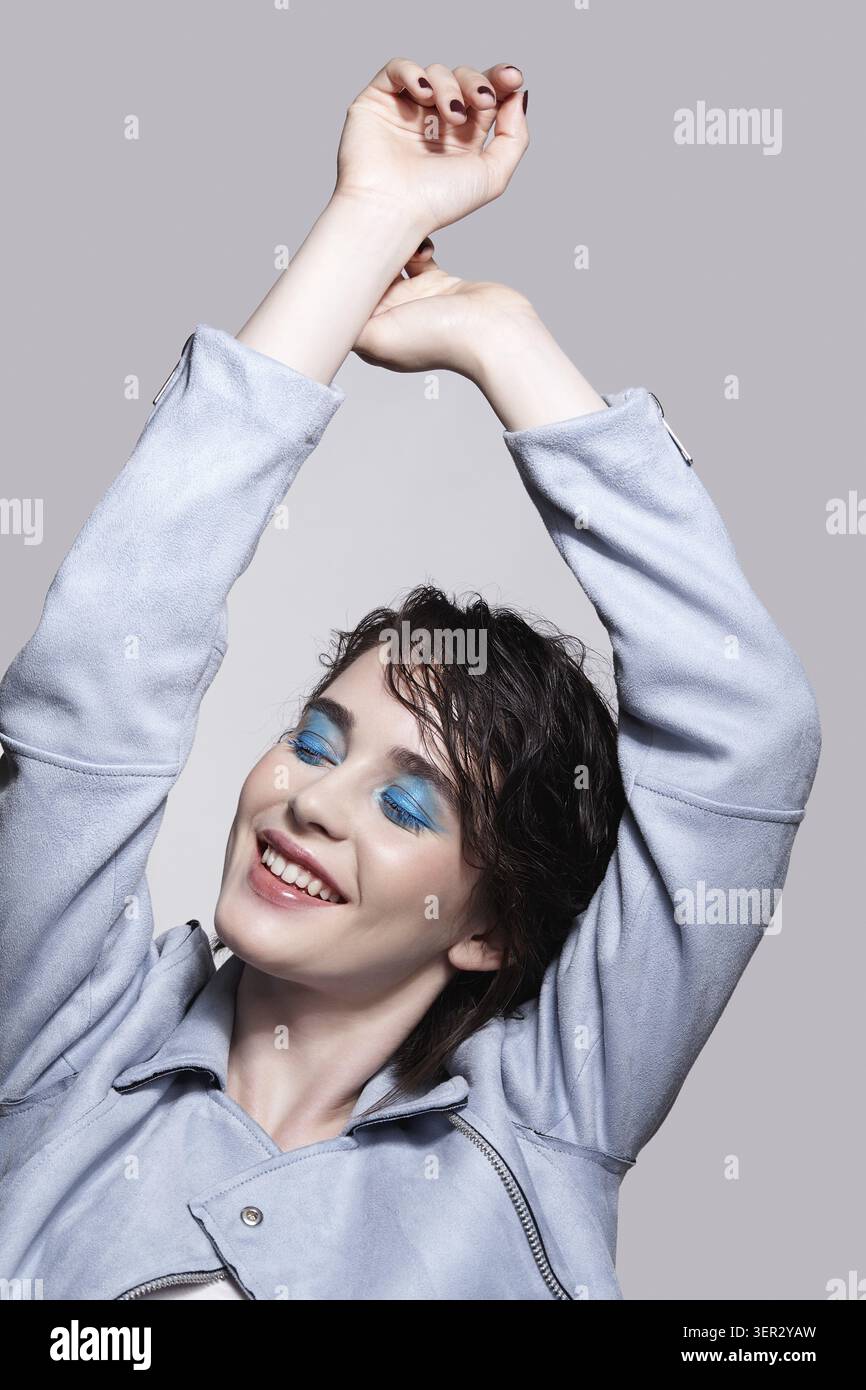 Ritratto di donna sorridente in giacca blu con le mani. Donna con inusuale bellezza trucco e capelli bagnati. Ragazza con una pelle perfetta, verde pistacchio colore Foto Stock