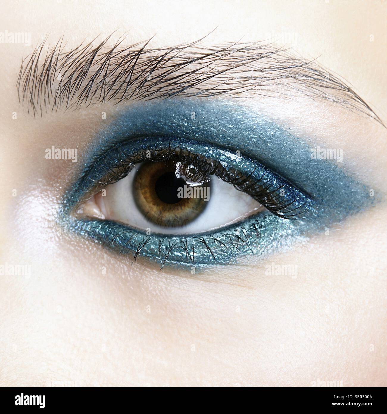 Primo piano macro di occhio umano femminile. Donna con trucco naturale per la sera. Ragazza con pelle perfetta e occhi fumé blu-verdi Foto Stock
