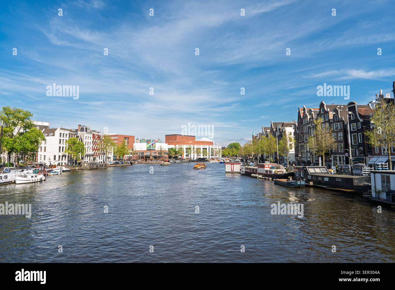 Vista panoramica del fiume Amstel e delle storiche case sui canali di Amsterdam, Paesi Bassi, il giorno della soleggiata Foto Stock