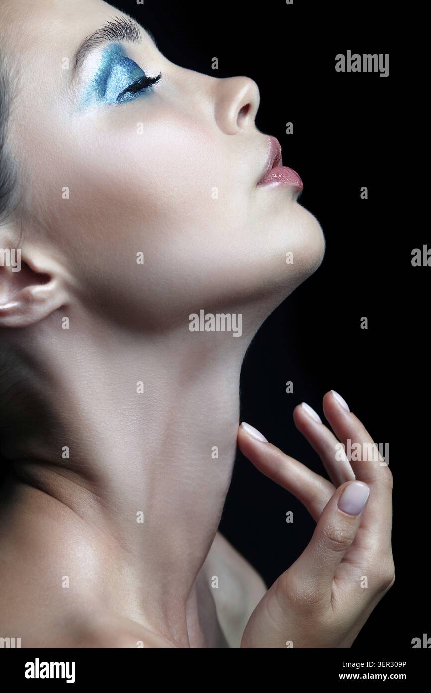 Bellezza ritratto di donna con la mano vicino al viso . Donna con la sera la bellezza del trucco. Ragazza con una pelle perfetta e blu-verde smoky occhi occhio ombre Foto Stock