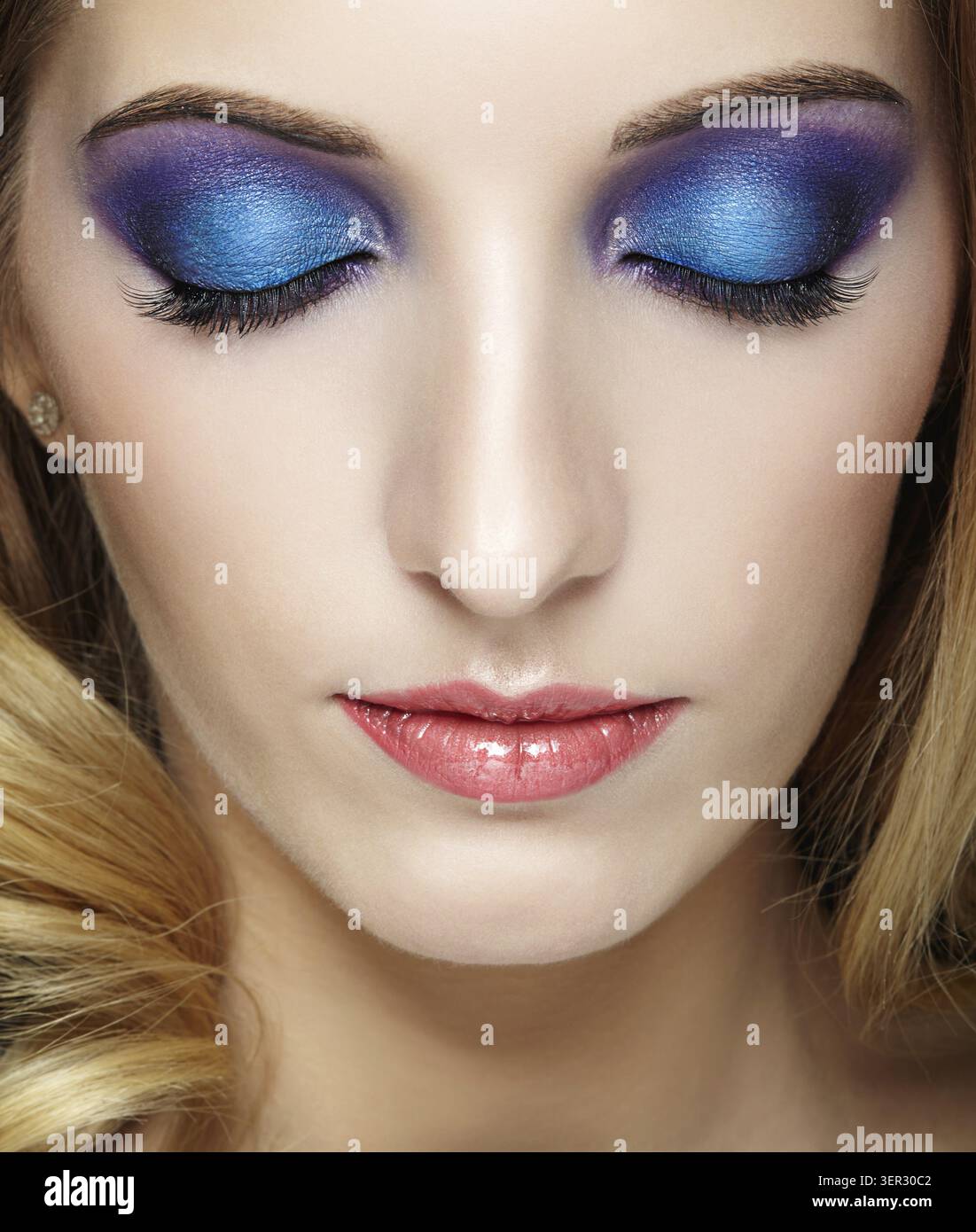 Closeup colpo di volto femminile con gli occhi chiusi con blu e viola trucco Foto Stock
