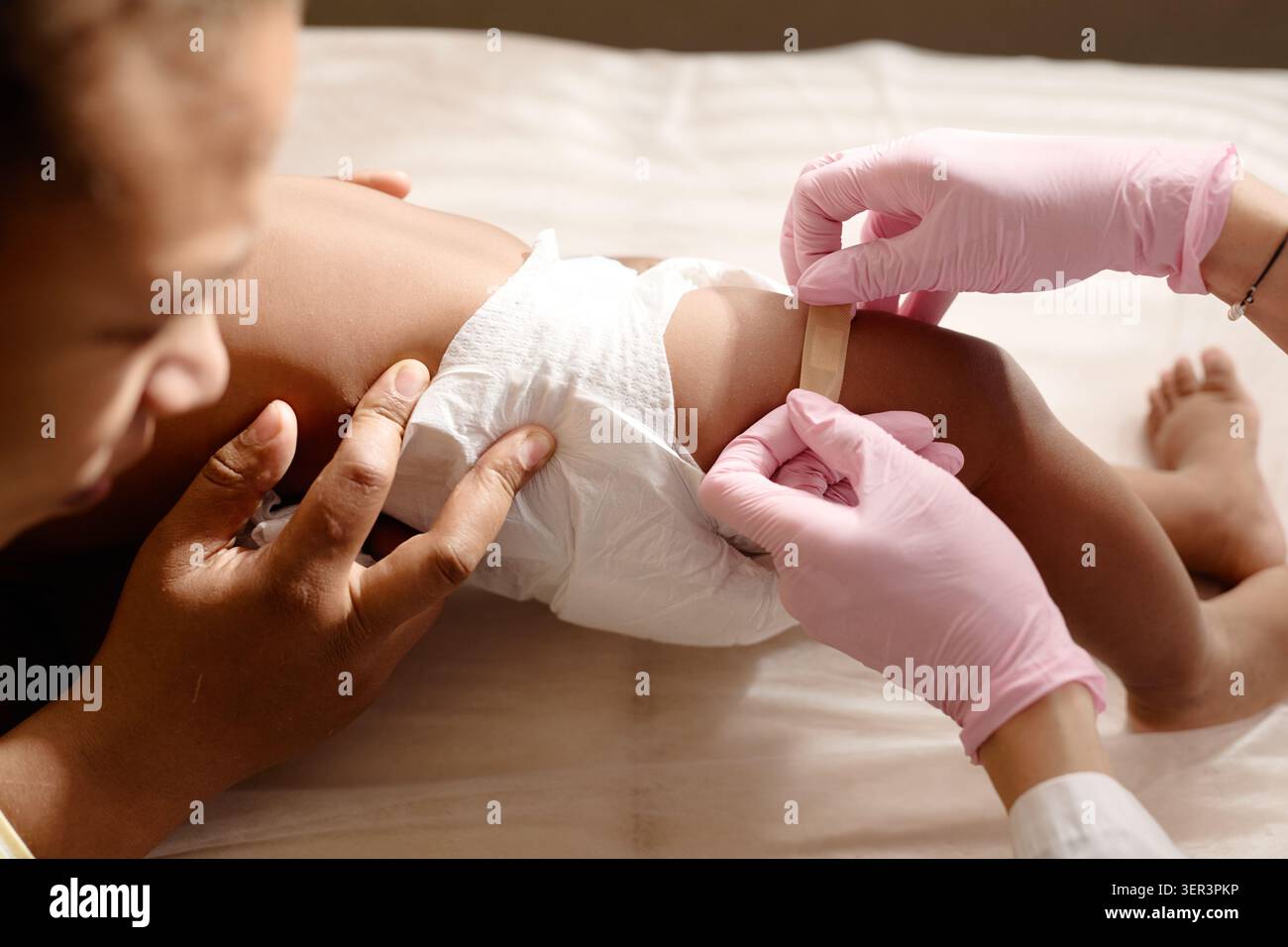 Black Mother Holding Baby durante la visita pediatrica Foto Stock