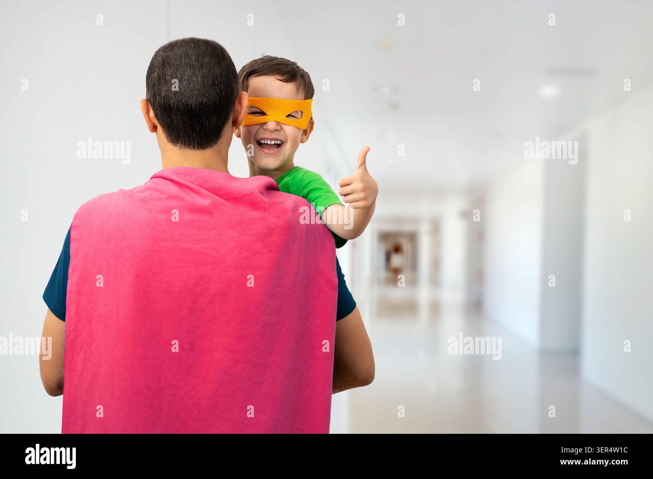 Il mio adorabile super papà.Kid che fa pollice su segno con le mani ridendo felicemente in ospedale Foto Stock