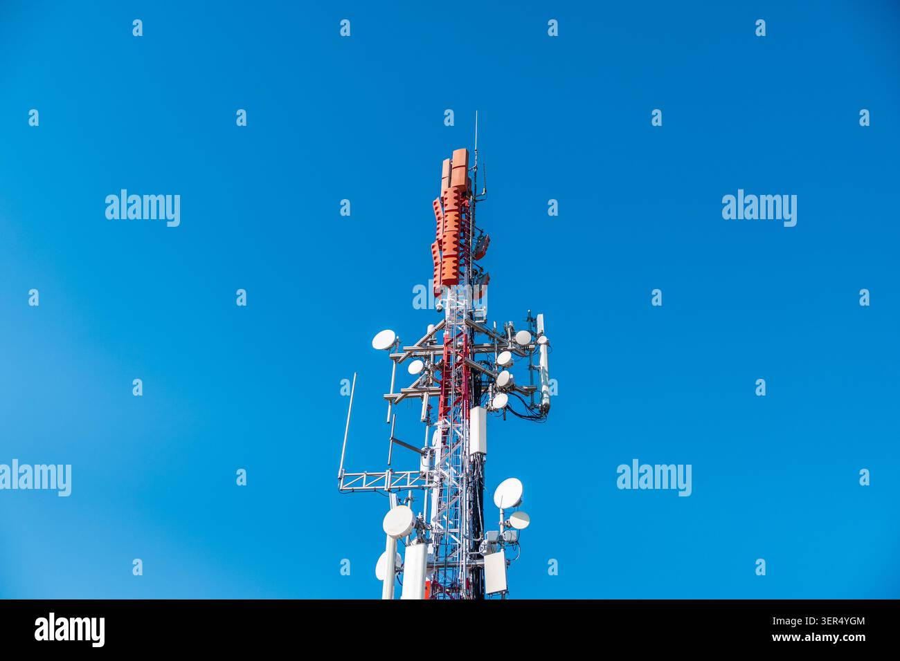 Torre di comunicazione cellulare con antenne e trasmettitori a microonde contro il cielo azzurro, moderna infrastruttura di telecomunicazioni Foto Stock