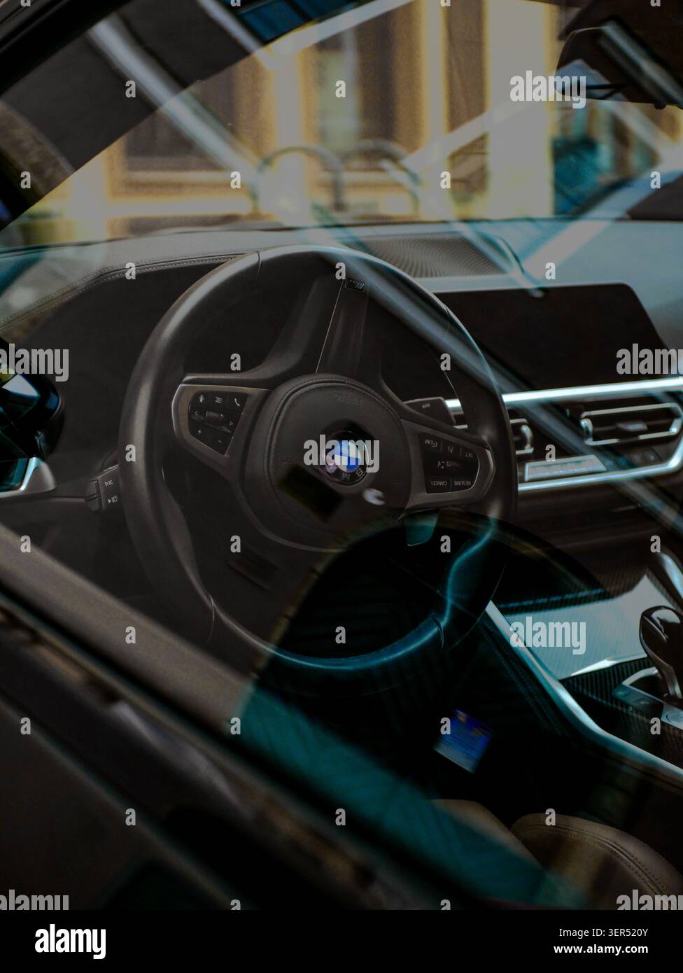 Vista attraverso una finestra BMW che rivela un interno moderno e lussuoso con riflessi di edifici storici della città. Foto Stock