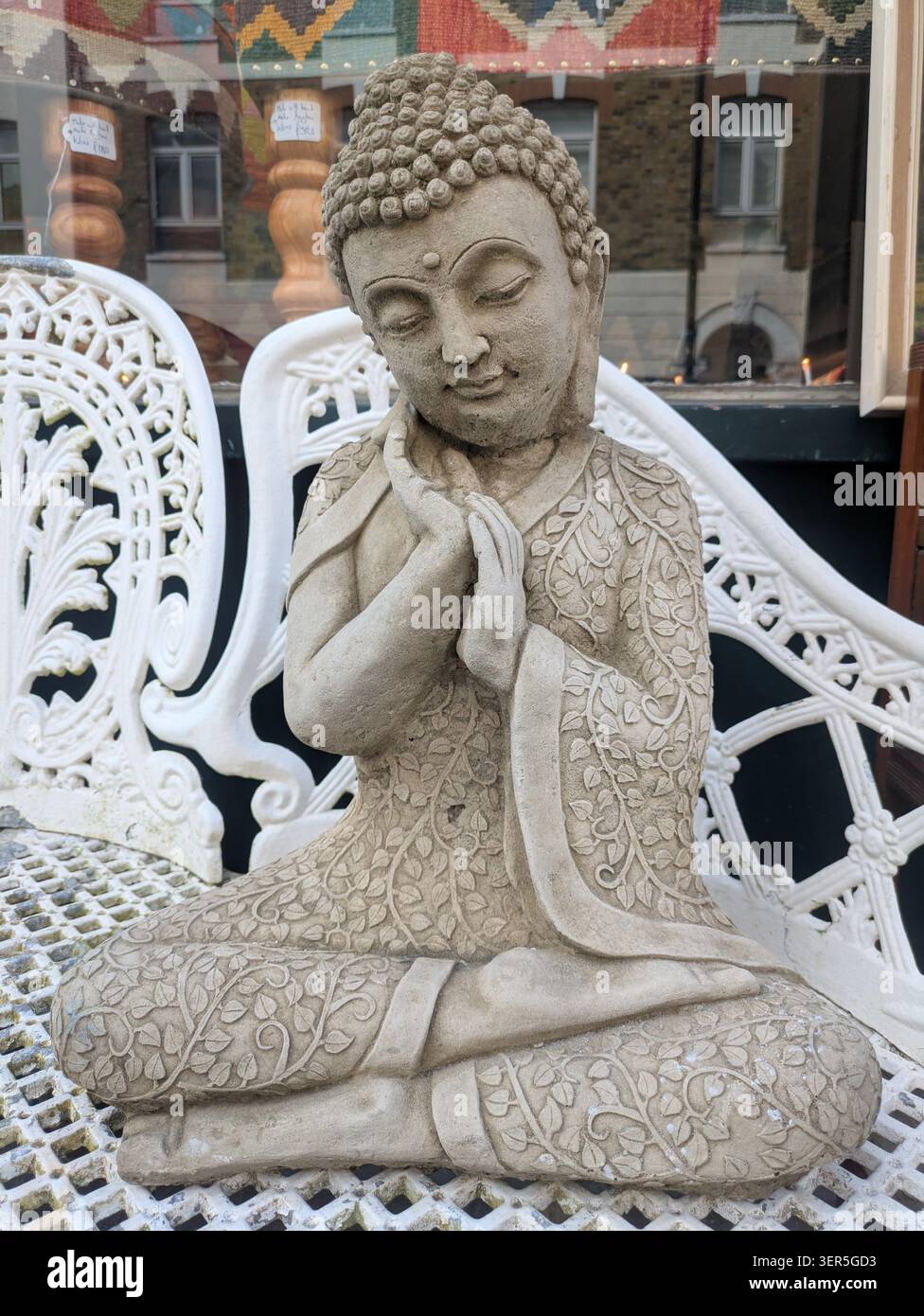 Buddha seduto sulla panchina bianca a mano sulla guancia Foto Stock