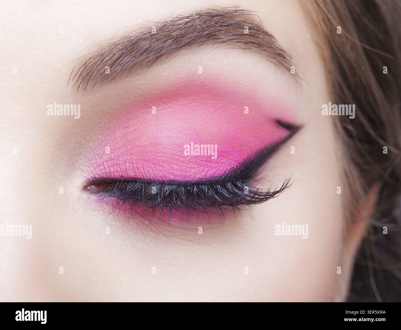 Primo piano macro di occhio umano femminile. Donna con trucco naturale per la sera. Ragazza con pelle perfetta e ombre rosa per gli occhi Foto Stock