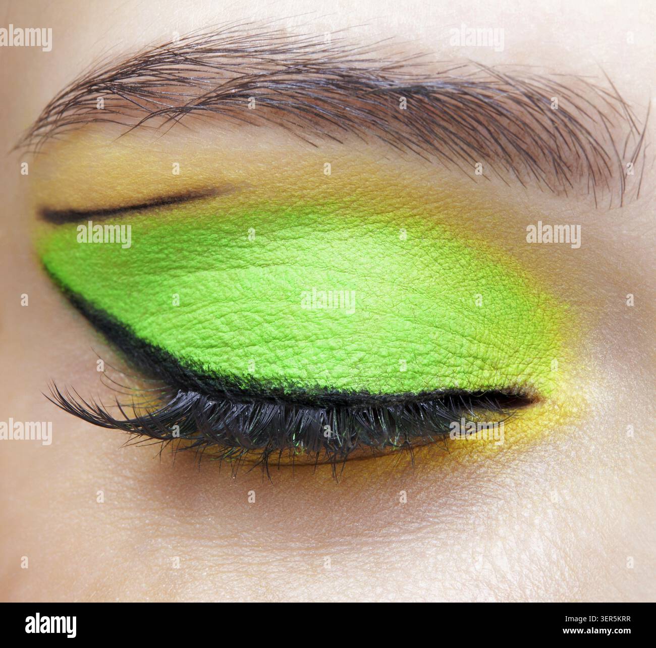 Foto macro di primo piano di un occhio umano femminile chiuso. Donna con un trucco di bellezza per il viso di moda. Ragazza con pelle perfetta e ombre verdi e gialle agli occhi Foto Stock