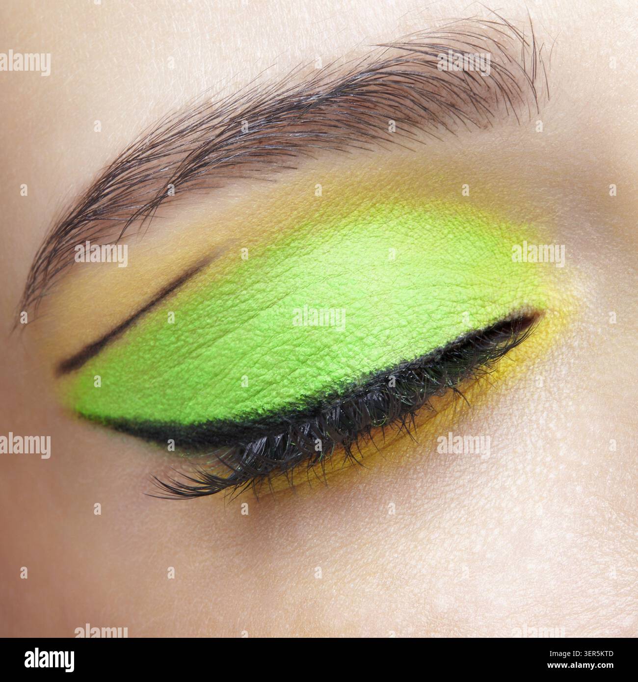 Foto macro di primo piano di un occhio umano femminile chiuso. Donna con un trucco di bellezza per il viso di moda. Ragazza con pelle perfetta e ombre verdi e gialle agli occhi Foto Stock