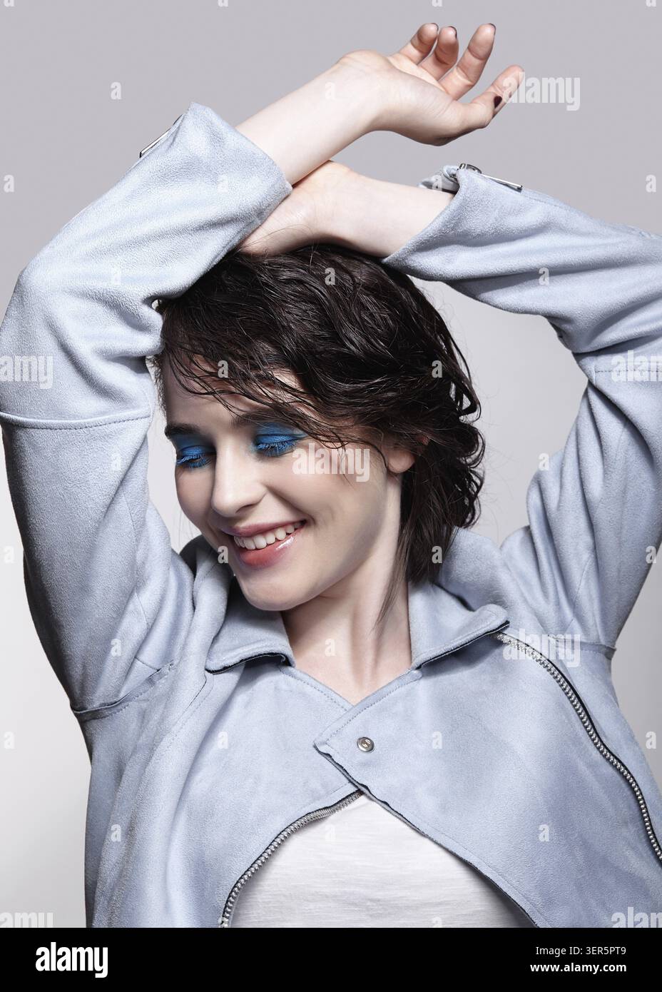 Ritratto di donna sorridente in giacca blu con le mani. Donna con inusuale bellezza trucco e capelli bagnati. Ragazza con una pelle perfetta, verde pistacchio colore Foto Stock
