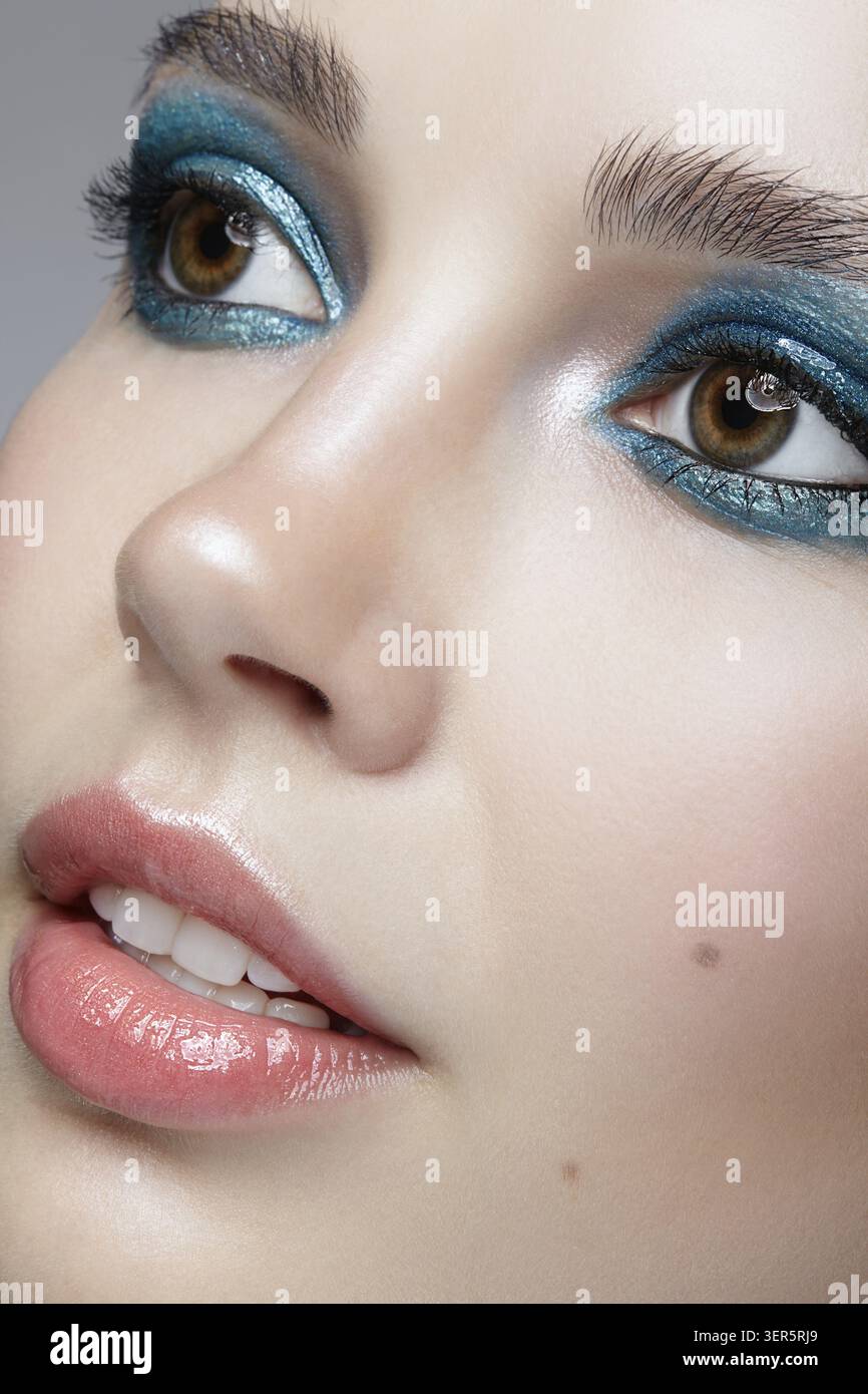 Macro Closeup ritratto di volto femminile. Donna con la sera la bellezza del trucco. Ragazza con una pelle perfetta e blu-verde smoky occhi occhio ombre Foto Stock