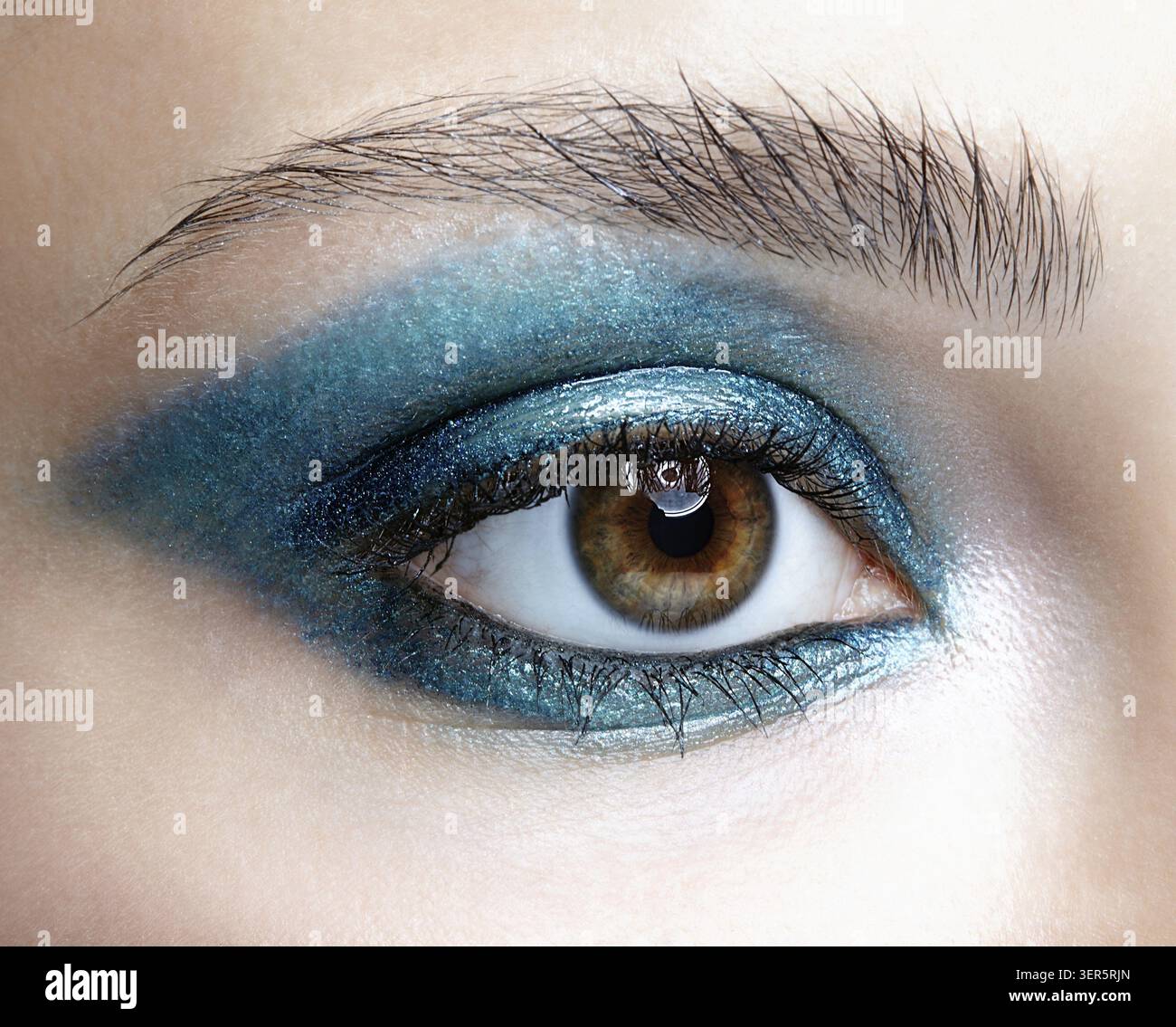 Primo piano macro di occhio umano femminile. Donna con trucco naturale per la sera. Ragazza con pelle perfetta e occhi fumé blu-verdi Foto Stock