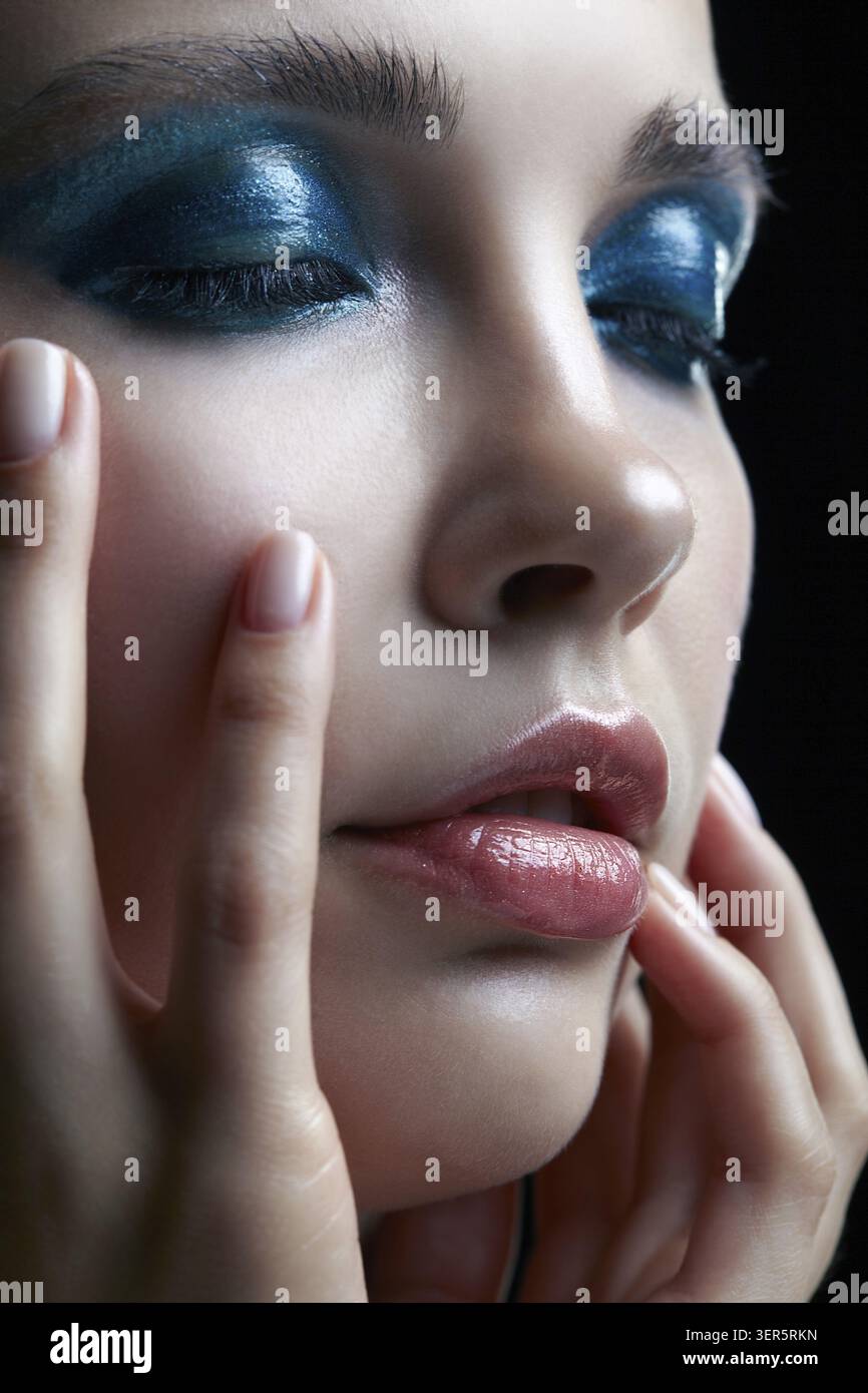 Macro Closeup ritratto di donna con la mano vicino al viso . Donna con la sera la bellezza del trucco. Ragazza con una pelle perfetta e blu-verde smoky occhi occhio ombre Foto Stock