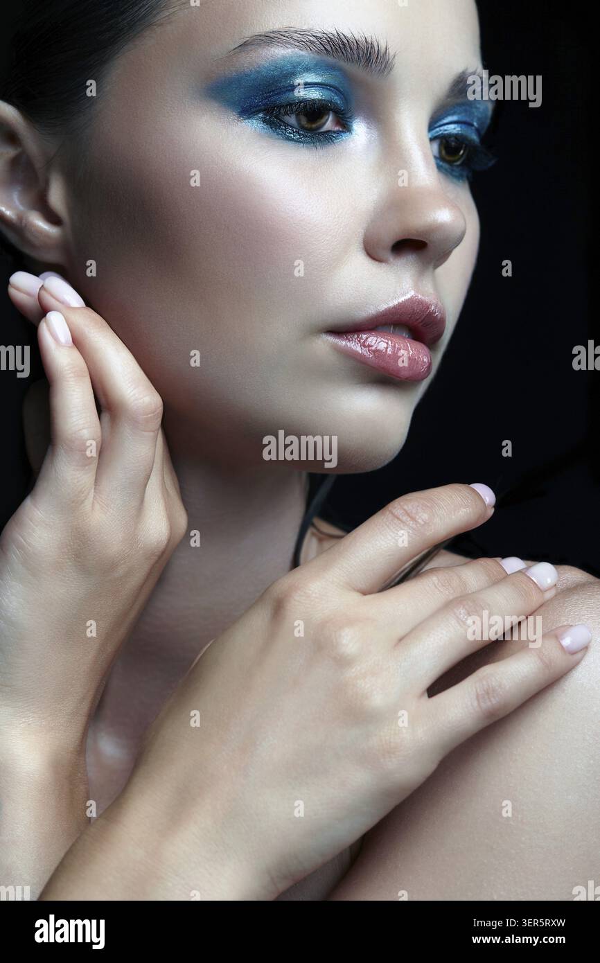 Bellezza ritratto di donna con la mano vicino al viso . Donna con la sera la bellezza del trucco. Ragazza con una pelle perfetta e blu-verde smoky occhi occhio ombre Foto Stock