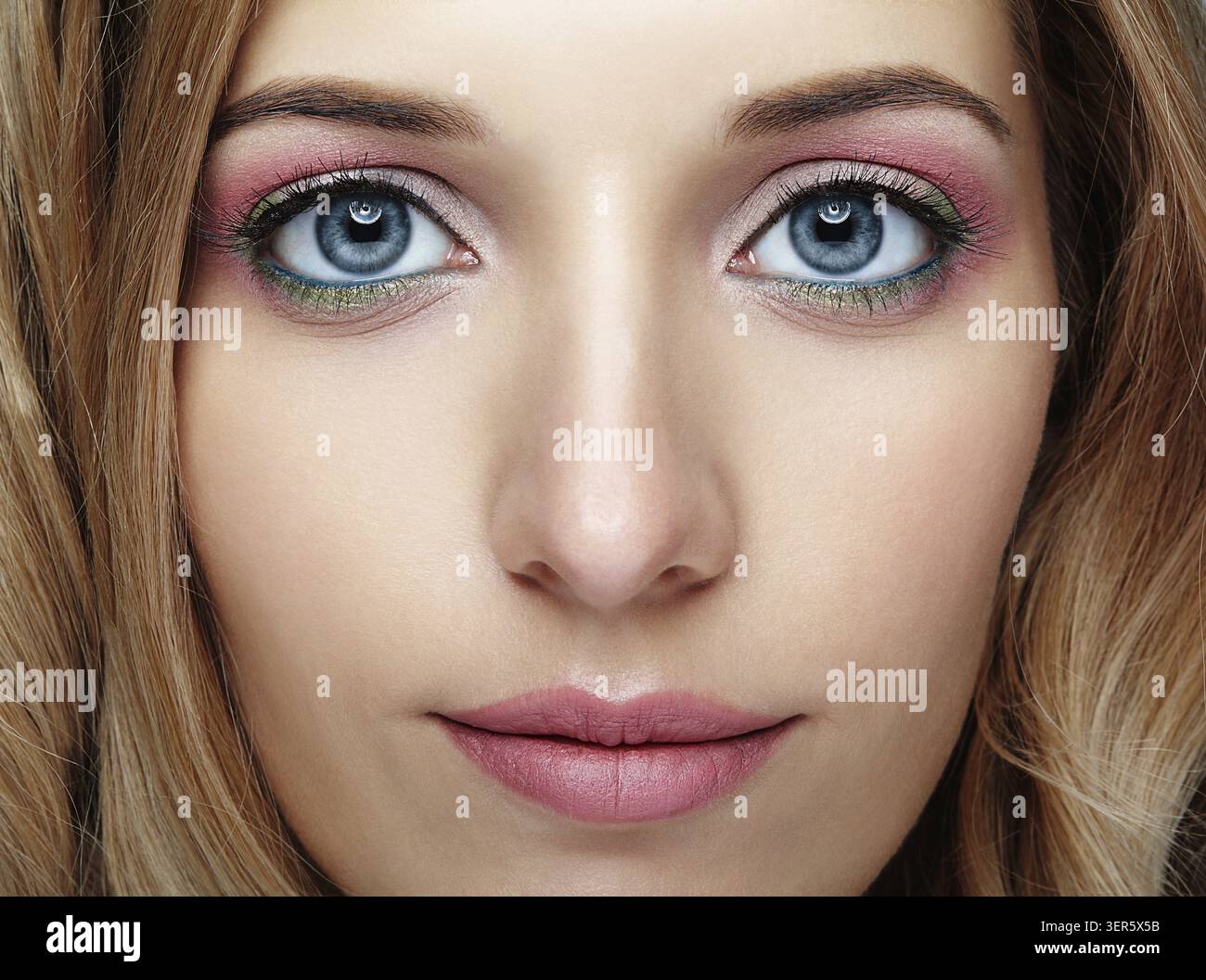 Closeup colpo di volto femminile con rosa e verde blu occhi trucco Foto Stock