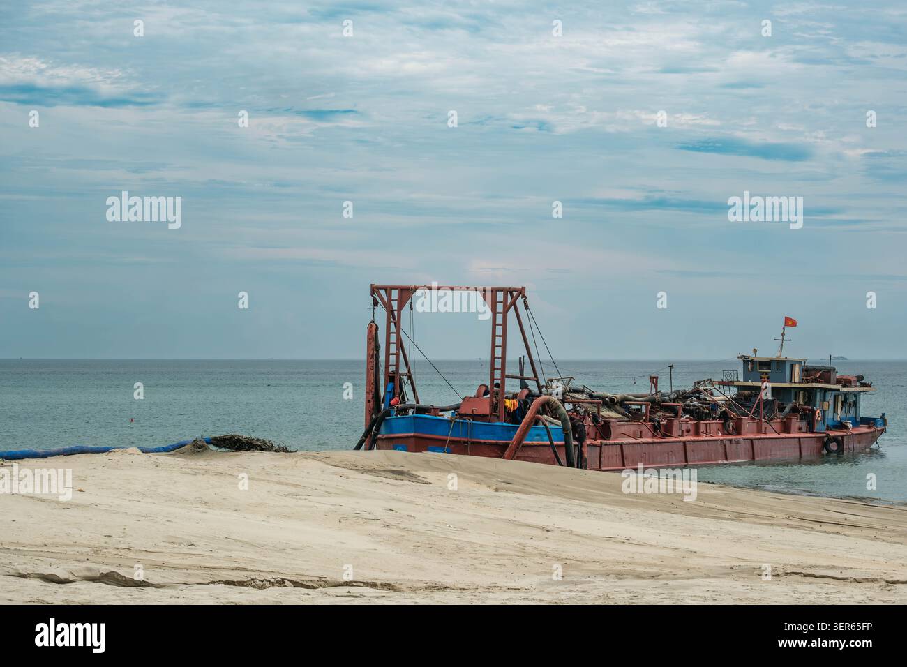 Imbarcazione industriale per dragaggio che lavora vicino a Sandy Beach Foto Stock