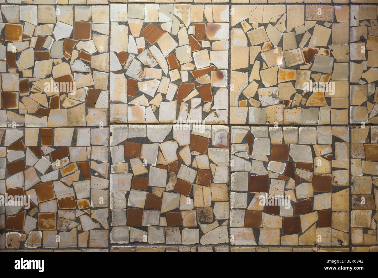 Vista dall'alto dettagliata di un mosaico realizzato con piastrelle di ceramica rotte. I toni terrosi di crema, beige e marrone creano un motivo astratto e strutturato. Foto Stock