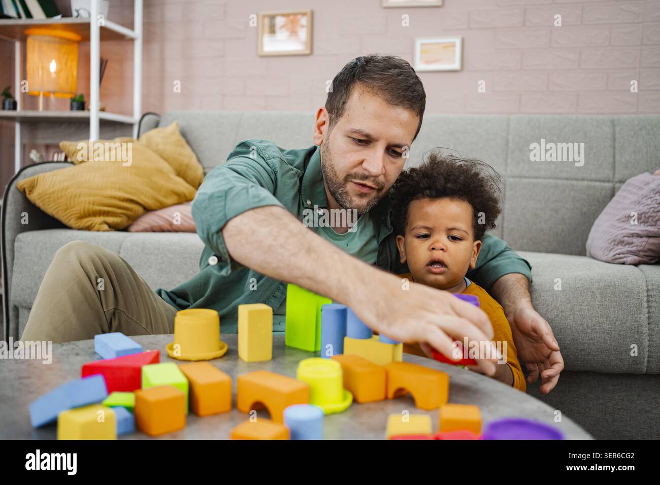 La famiglia si unisce attraverso un colorato blocco di gioco a casa Foto Stock