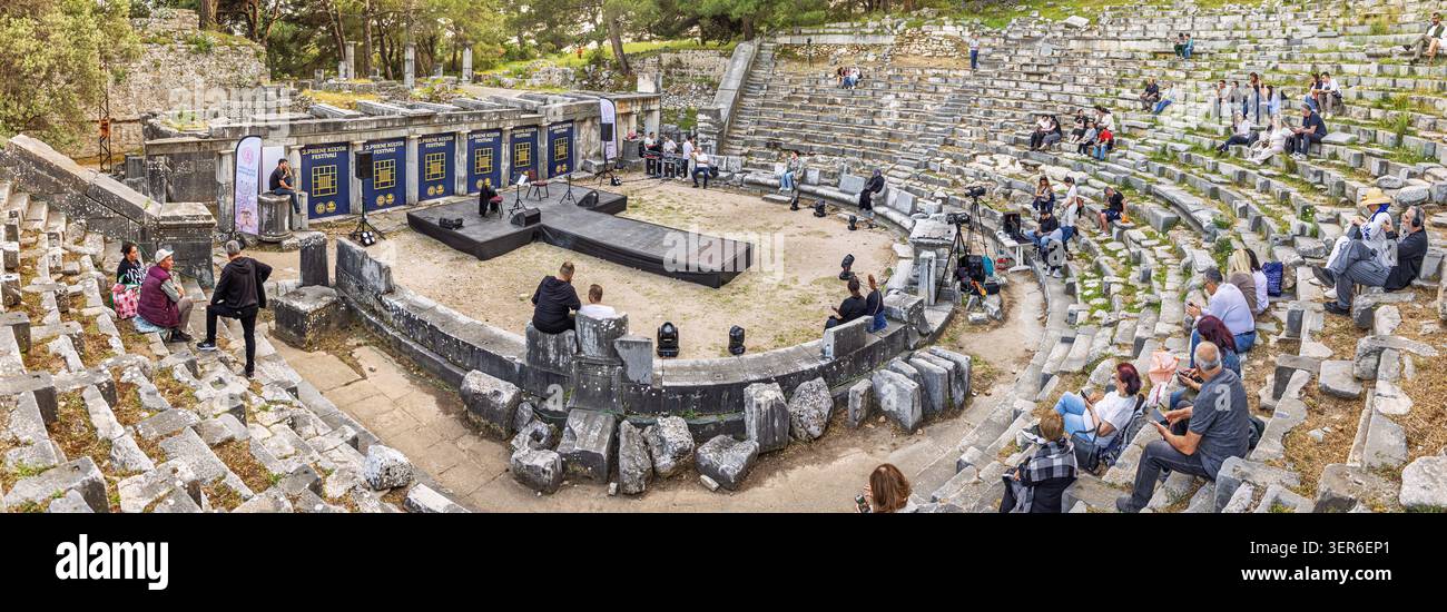 9 maggio 2026, Gullubahce, Turkiye: Persone che partecipano a un evento culturale all'interno delle antiche rovine del teatro Priene, su gradini di pietra Foto Stock