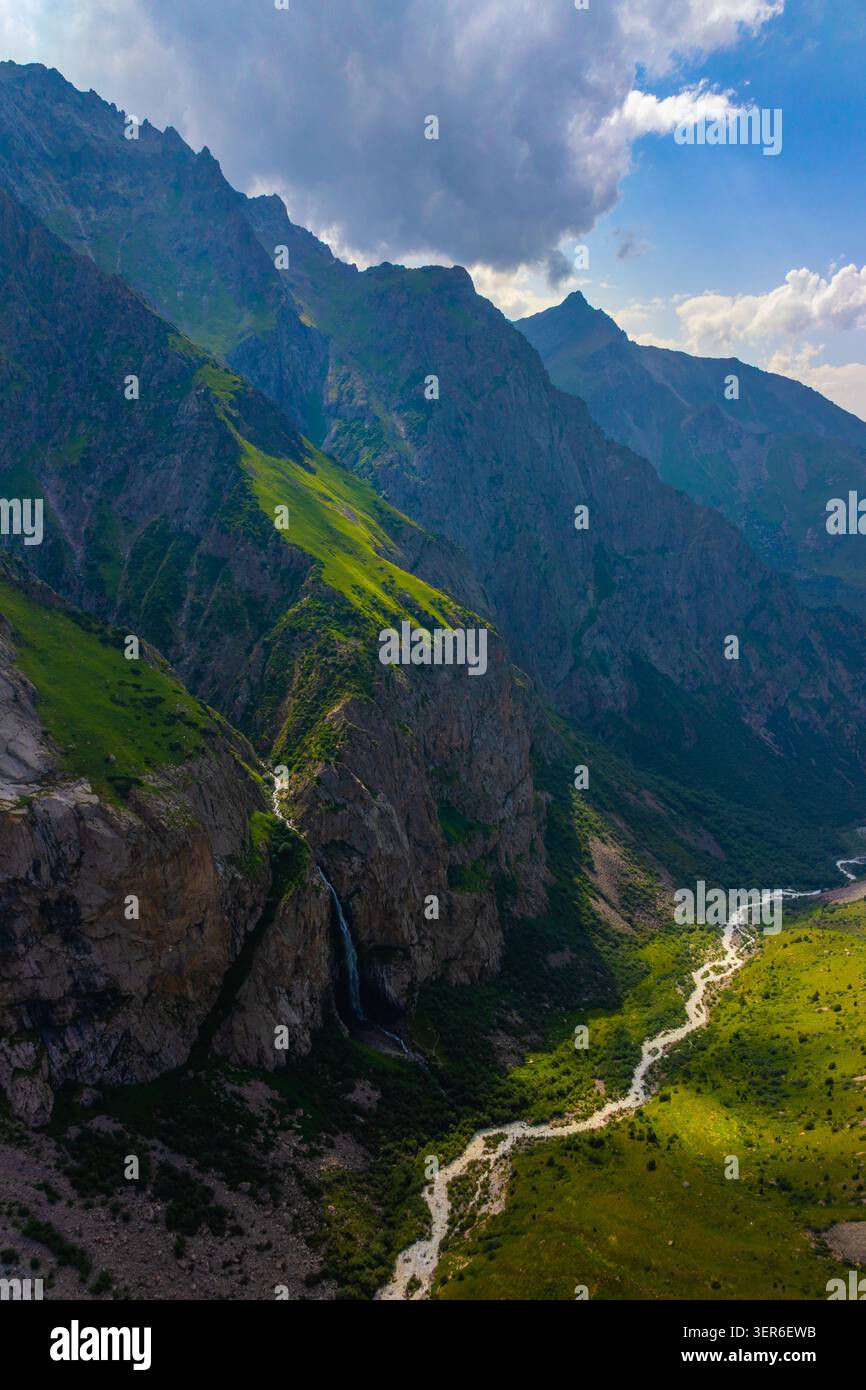 La vista aerea cattura le aspre catene montuose con pendii ripidi e vibrante erba verde. Un tortuoso fiume scorre attraverso la valle, con una splendida Foto Stock