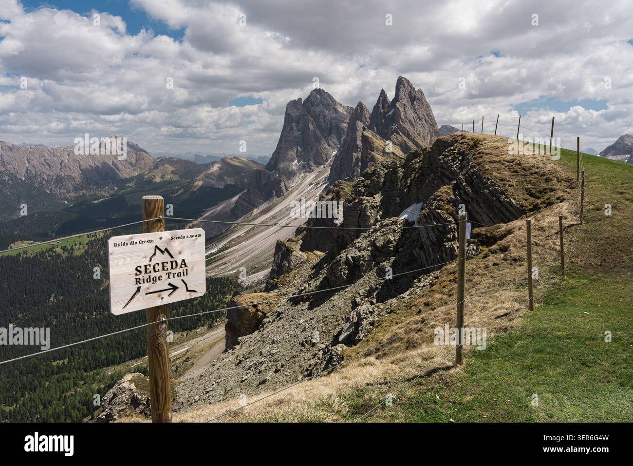 Cartello in legno per il Seceda Ridge Trail, con spettacolari cime rocciose e pendii erbosi nelle Dolomiti italiane, scenografiche escursioni estive alpine Foto Stock