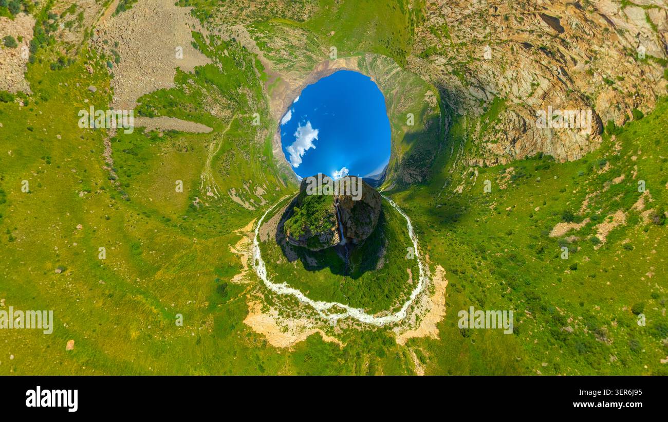 La vista aerea cattura il vasto paesaggio montano caratterizzato da scogliere rocciose e verdi colline ondulate. Inverte la proiezione del piccolo pianeta. Valle tranquilla con rive Foto Stock