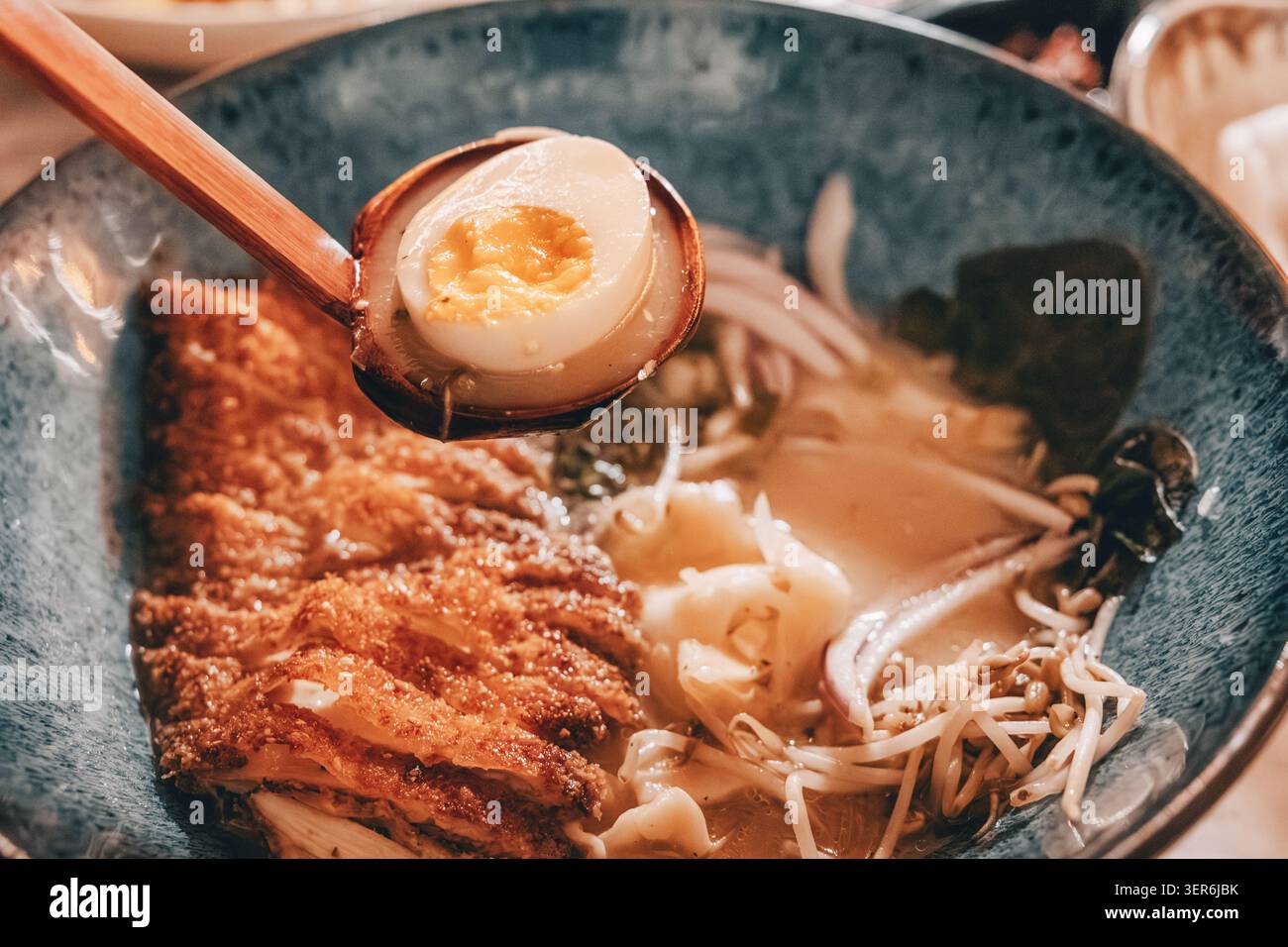 Ciotola di ramen giapponese con tonkatsu croccante, uova sode marinate di soia, spaghetti, germogli di soia e brodo da servire Foto Stock