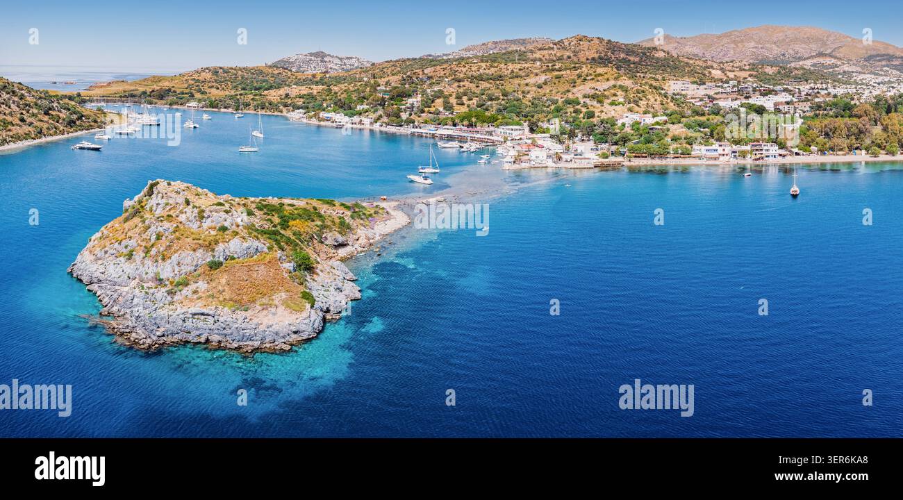 Gumusluk, Bodrum, goditi una calda giornata estiva, mostrando l'Isola dei conigli e gli yacht privati che ancorano nel mare turchese dell'Egeo Foto Stock