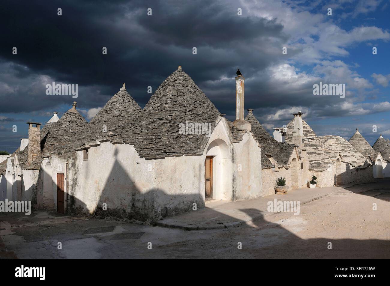 Italia, Puglia, Alberobello: trulli, case in pietra secca (senza Malta), con pareti bianche e tetti a forma di cono ricoperti di lastra calcarea Foto Stock