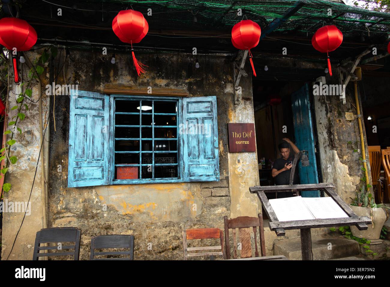 Persona all'ingresso di un Cafe' in un vecchio colorato edificio tradizionale a Hoi An Vietnam Foto Stock