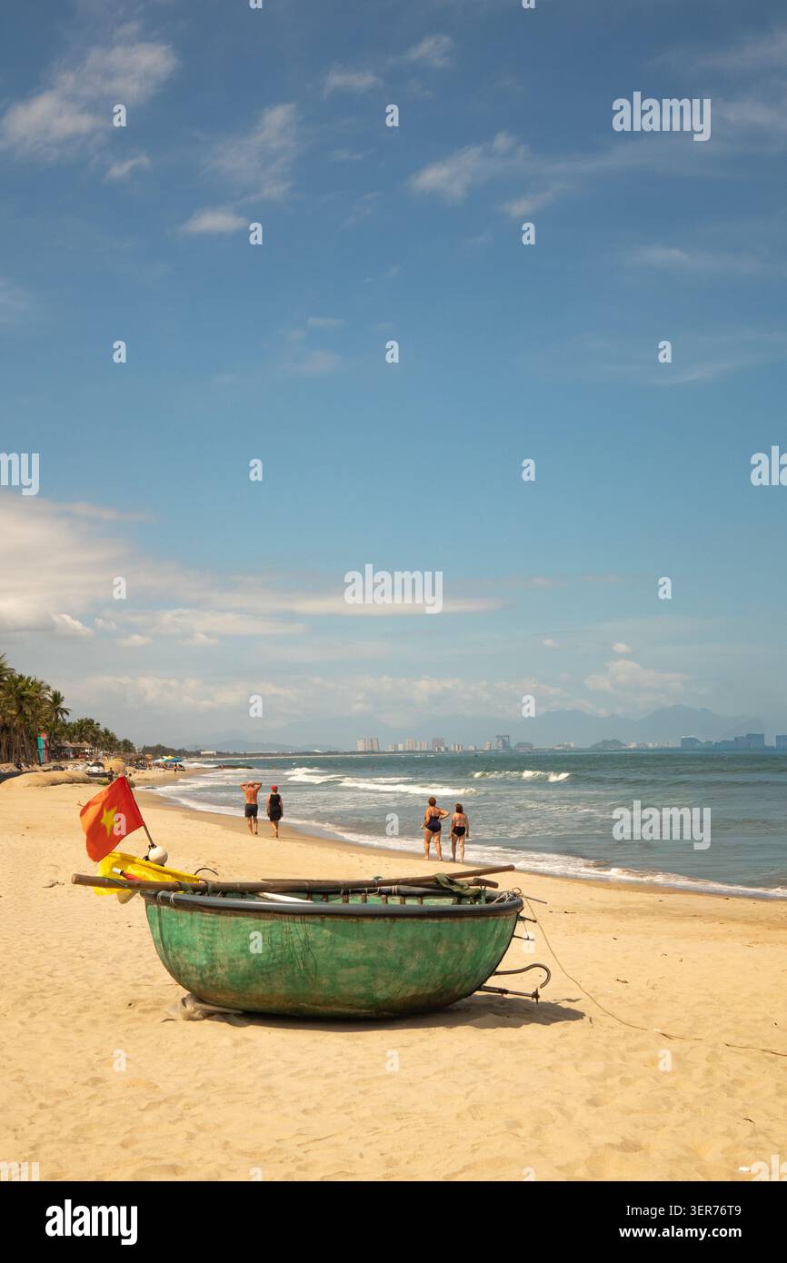 Piccola barca da pesca verde circolare con bandiere colorate, reti e attrezzature da pesca. Sulla spiaggia di Cua dai vicino a Hoi An Vietnam Foto Stock