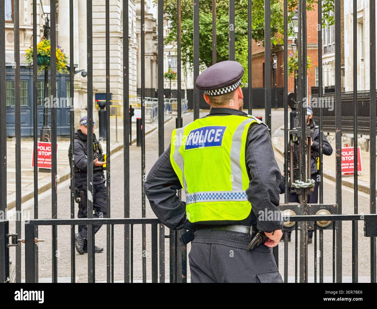 Londra, Inghilterra, Regno Unito - 16 maggio 2026: Agente di polizia della Metropolitan Police che parla con agenti di polizia armati alle porte di Downing Street - Immagine stock catturata con smartphone