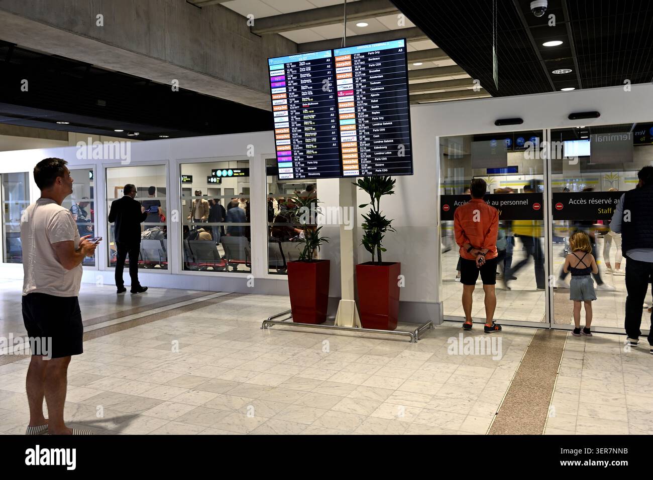 Bell'aeroporto con un uomo che guarda il tabellone degli arrivi dei voli Foto Stock