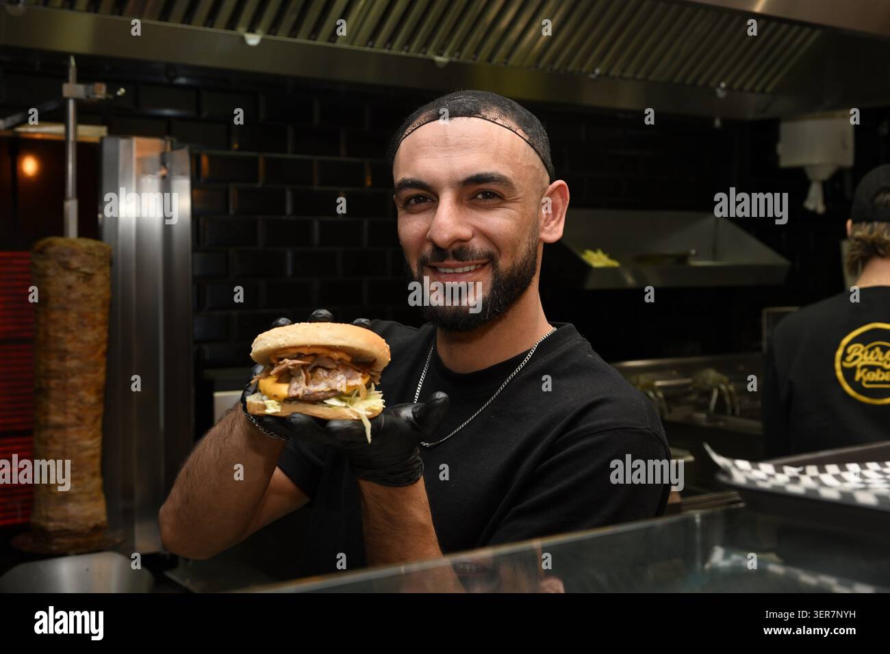All'interno del ristorante fast food Burger K viene mostrato un gustoso panino ripieno di kabab dal personale, Nizza Francia Foto Stock