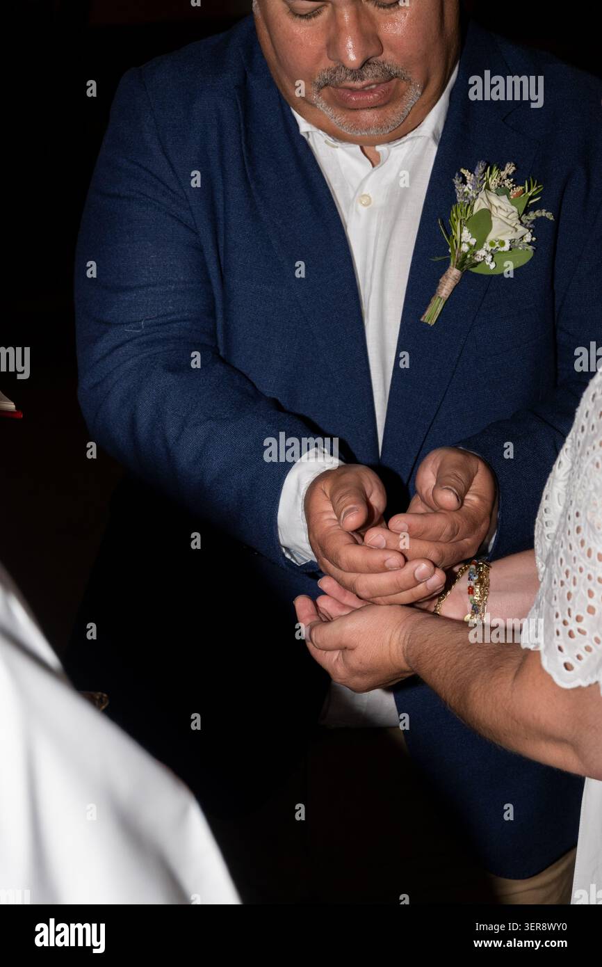 Sposo e sposa eseguono un rituale che condivide le mani durante un matrimonio Foto Stock