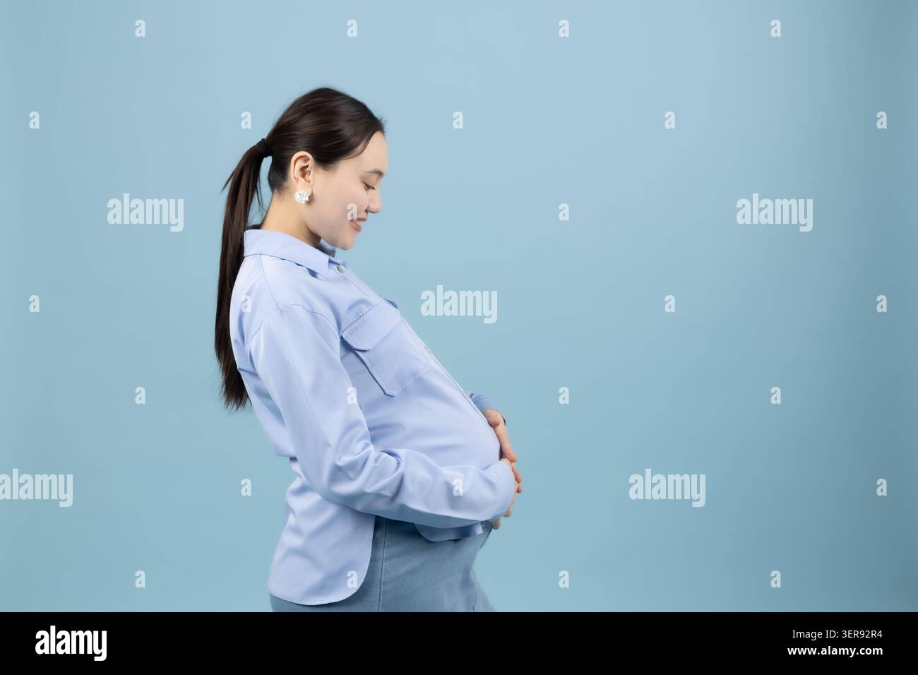 Donna che tiene lo stomaco e sorride Foto Stock