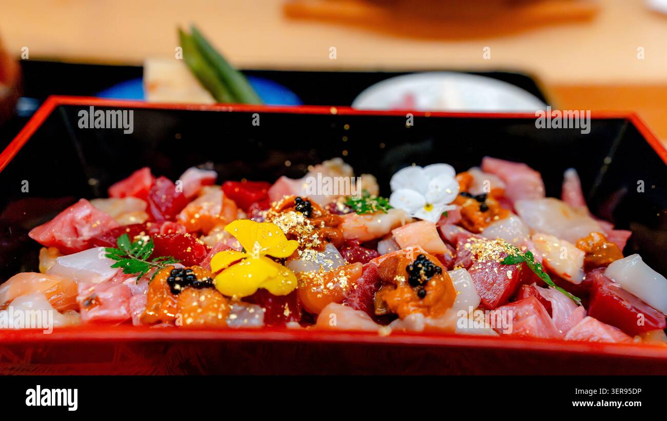 Colorato piatto di sushi chirashi in un ristorante giapponese di Tokyo, condito con tonno rosso Miyagi del Pacifico, sashimi di pesce assortito, uova, fiori commestibili, e. Foto Stock