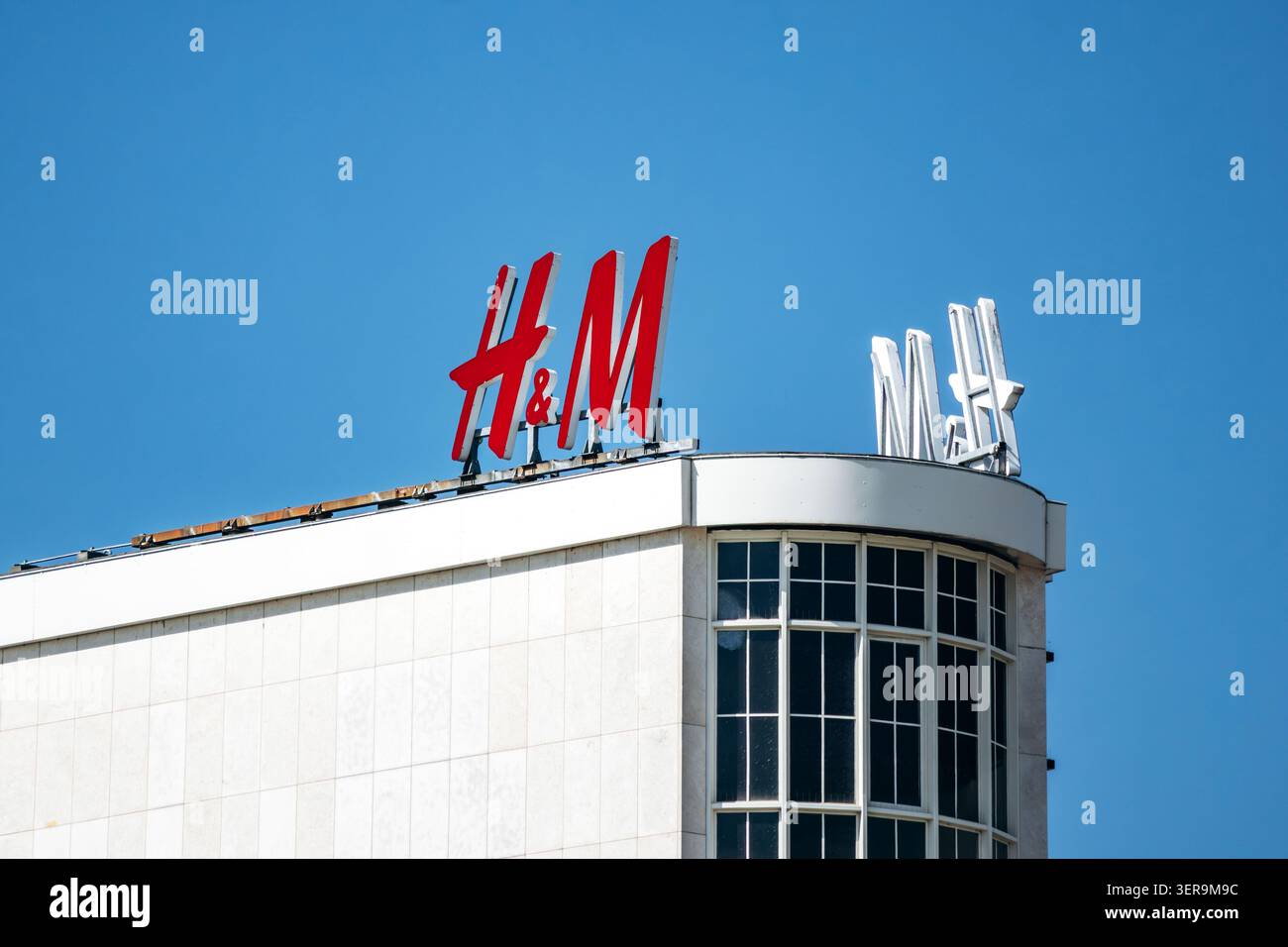 Hannover, Germania - 21 aprile 2026: Cartello HM sul tetto su una facciata bianca di un edificio di vendita al dettaglio, contro un cielo azzurro Foto Stock