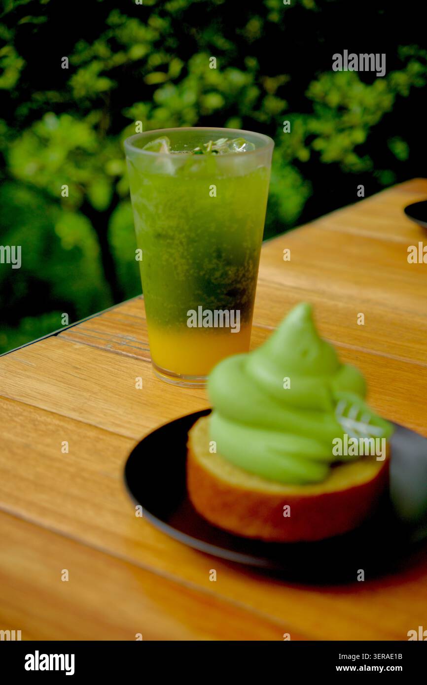 Bevanda con tè verde e dessert matcha su un tavolo di legno in una caffetteria sull'isola di Jeju, Corea del Sud, che mette in risalto la cultura del tè e il turismo gastronomico coreano. Foto Stock