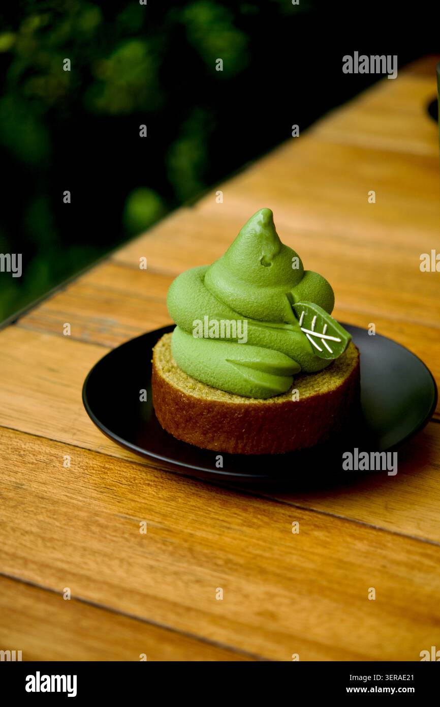 Dessert con crema di matcha servito su un piatto nero in un caffè sull'isola di Jeju, Corea del Sud, ispirato alla cultura del tè regionale e alle tradizioni culinarie. Foto Stock