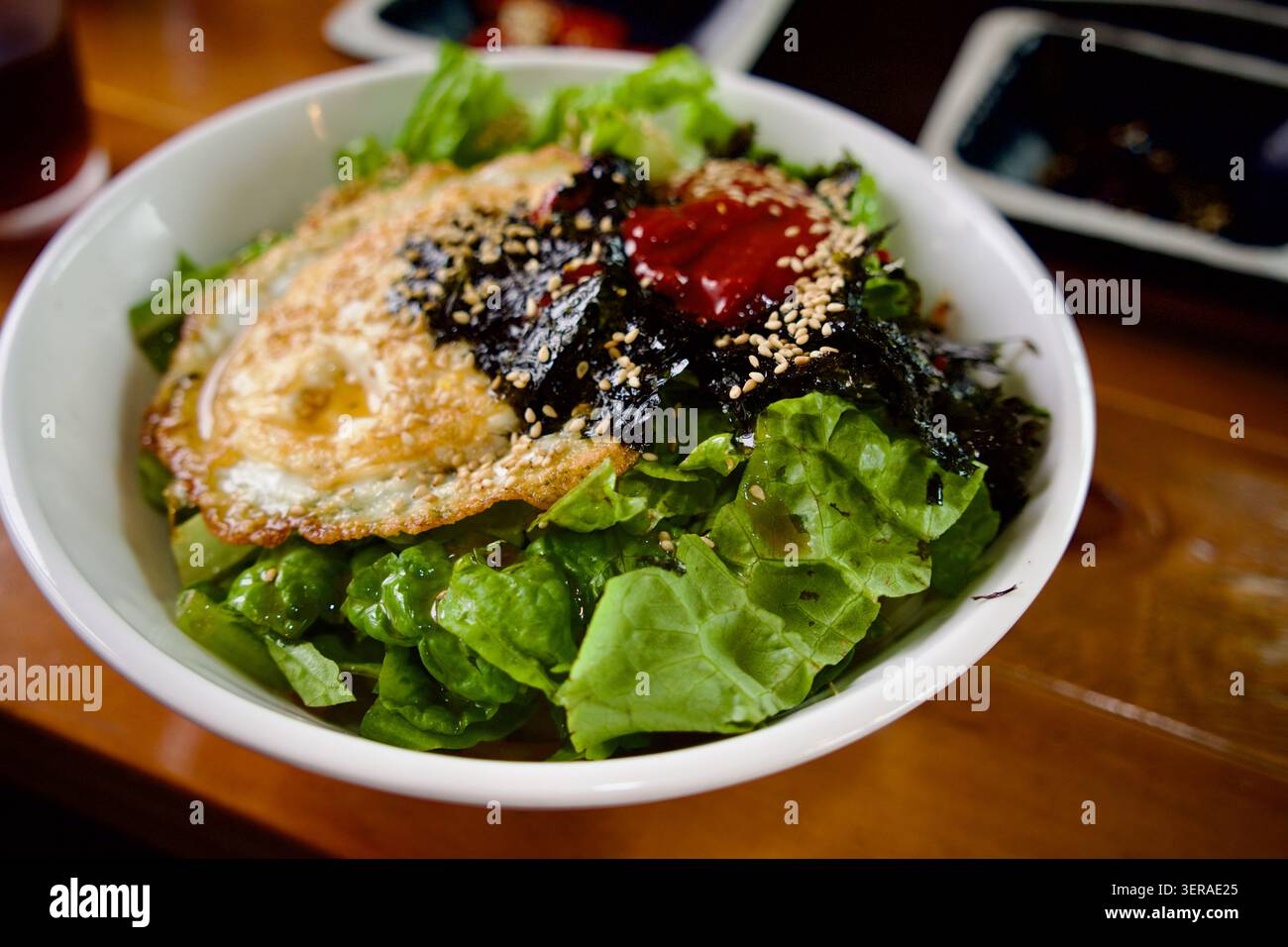 Sana ciotola di riso con verdure fresche, alghe e condimenti serviti in un ristorante sull'isola di Udo, nella provincia di Jeju, Corea del Sud. Foto Stock