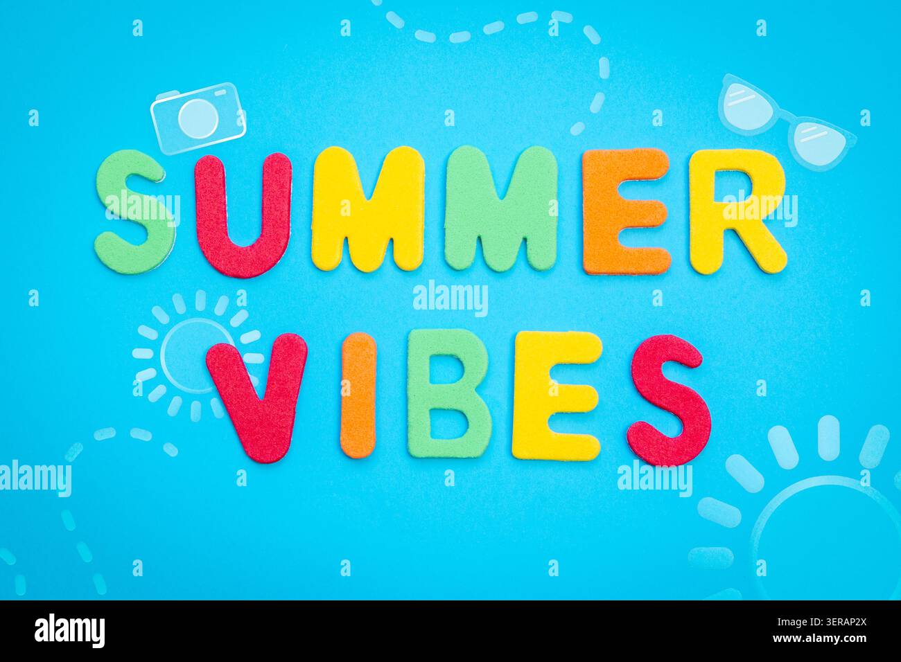 Lettere in schiuma vibranti che scrivono Summer Vibes su sfondo blu con icone assolate per un tema di vacanza divertente. Foto Stock