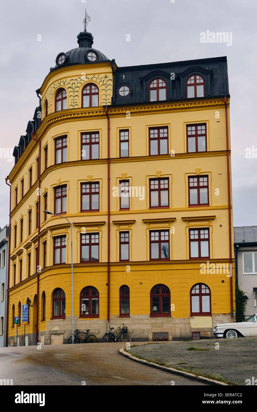 Karlskrona, Svezia - 14 settembre 2025: Veduta di un classico edificio residenziale giallo con un tetto di mansarda nera e una piccola cupola su un ripido decor di strada Foto Stock
