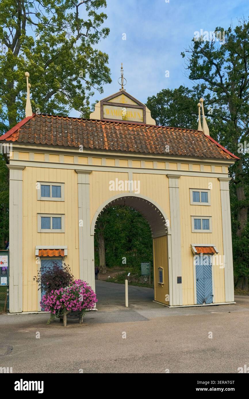 Karlskrona, Svezia - 13 settembre 2025: Vista dello storico edificio in legno giallo di Wamoparken con il suo ingresso ad arco, il tetto piastrellato e il rosa Foto Stock