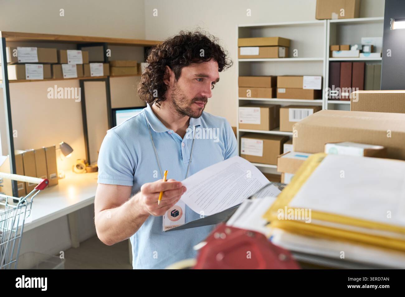 Uomo che controlla i documenti degli ordini al punto di ritiro per la consegna Foto Stock