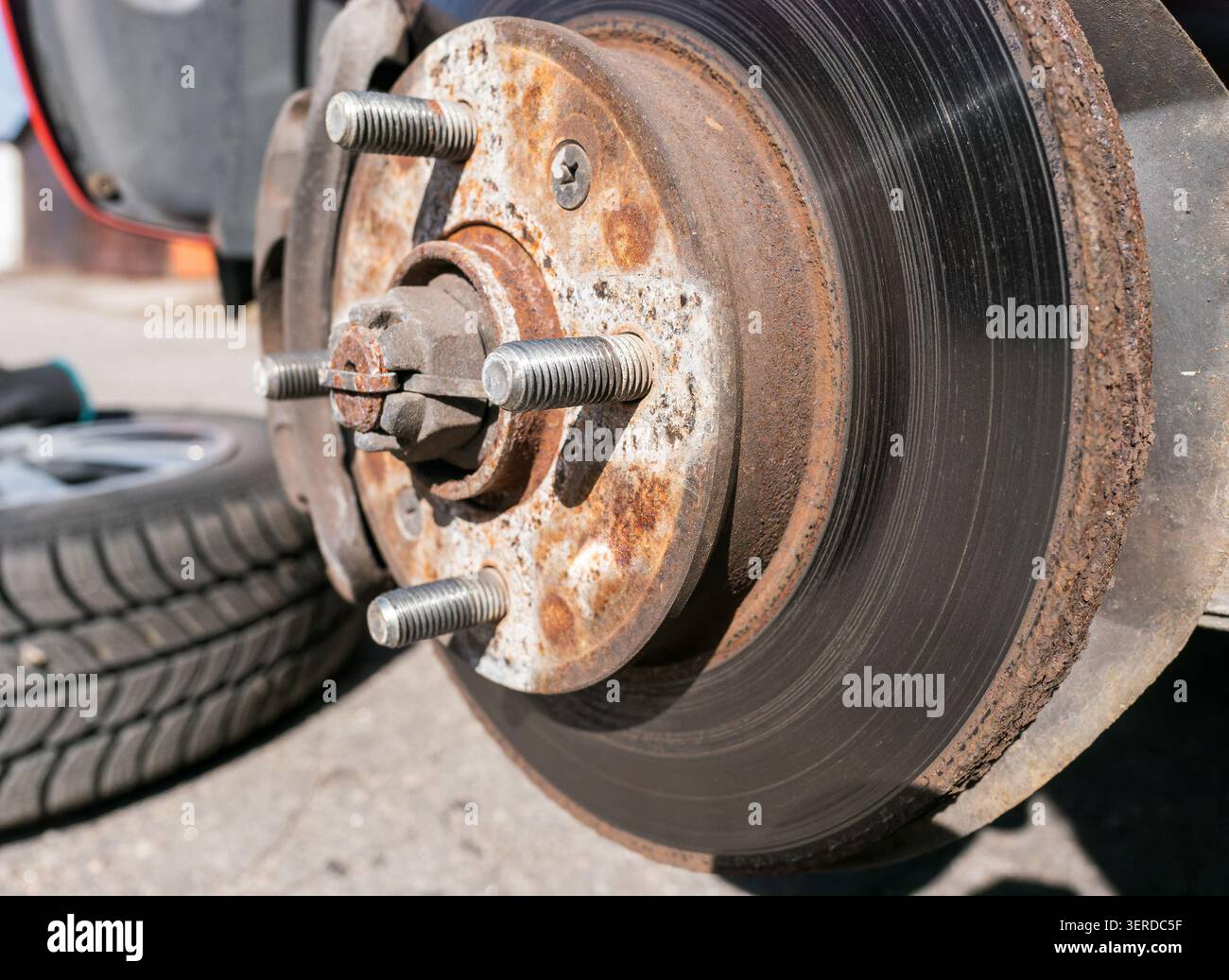 Fotografie professionali del settore automobilistico che mostrano un sistema frenante a disco danneggiato dopo la rimozione della ruota, evidenziando i problemi di sicurezza più comuni Foto Stock