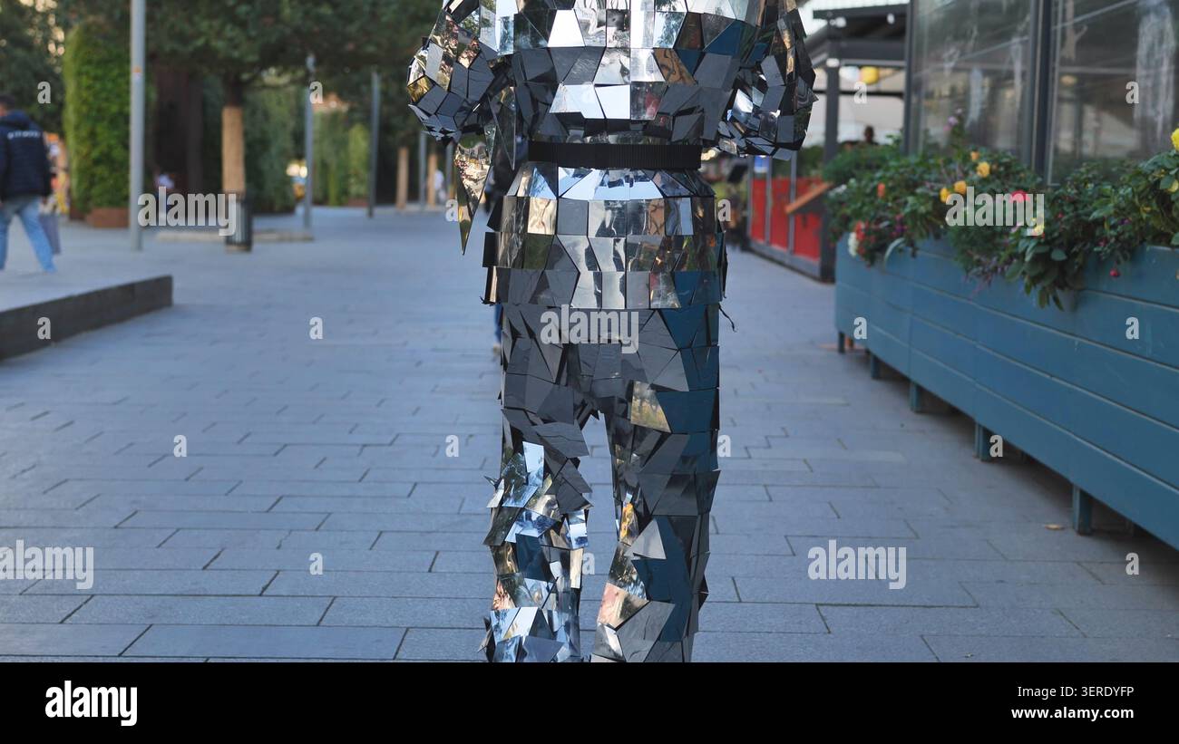 Vista posteriore di una persona che indossa un costume completo di specchi argentati su un passaggio pedonale Foto Stock