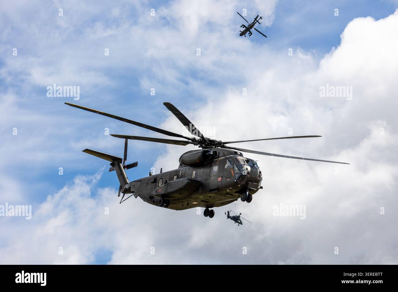 Trasporto militare elicotteri vola cielo nuvoloso accompagnato formazione elicotteri d'attacco. Potenti rotorcraft dimostrano la difesa della mobilità aerea Foto Stock