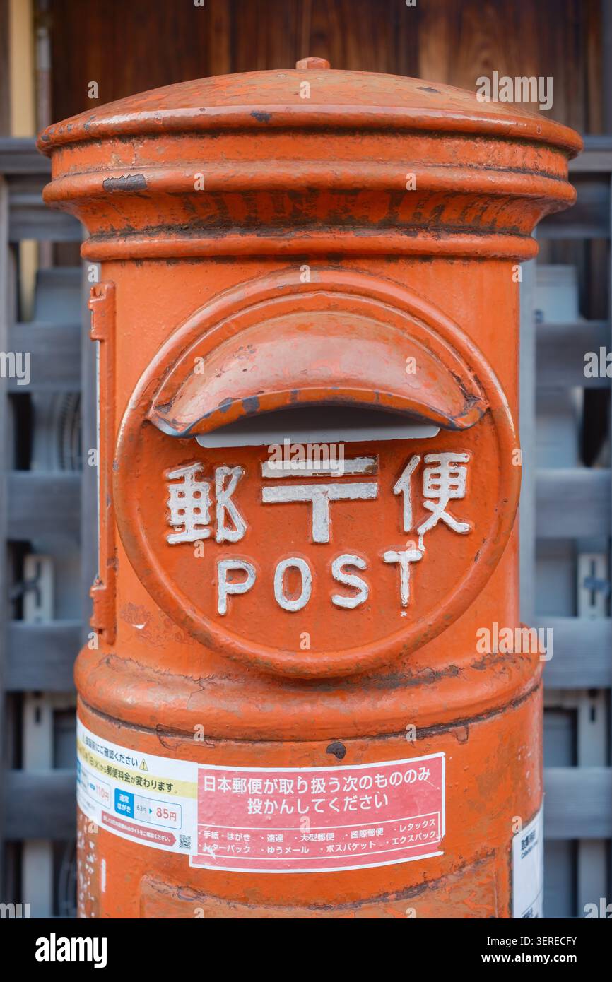 Classico box da posta a colonna in ghisa rossa con scritta kanji giapponese e testo inglese all'aperto, Kyoto, Giappone Foto Stock