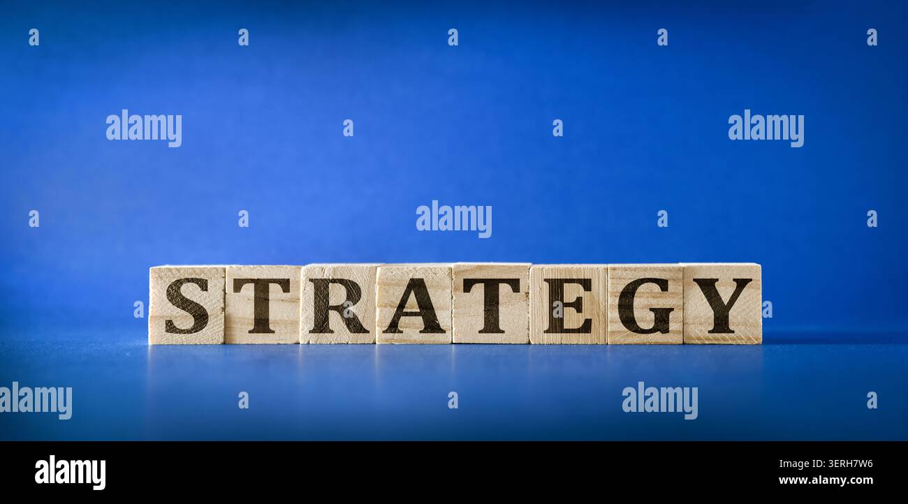 Strategia di ortografia in blocchi di legno su sfondo blu, che simboleggia i concetti di pianificazione, visione aziendale, leadership e successo aziendale. Foto Stock